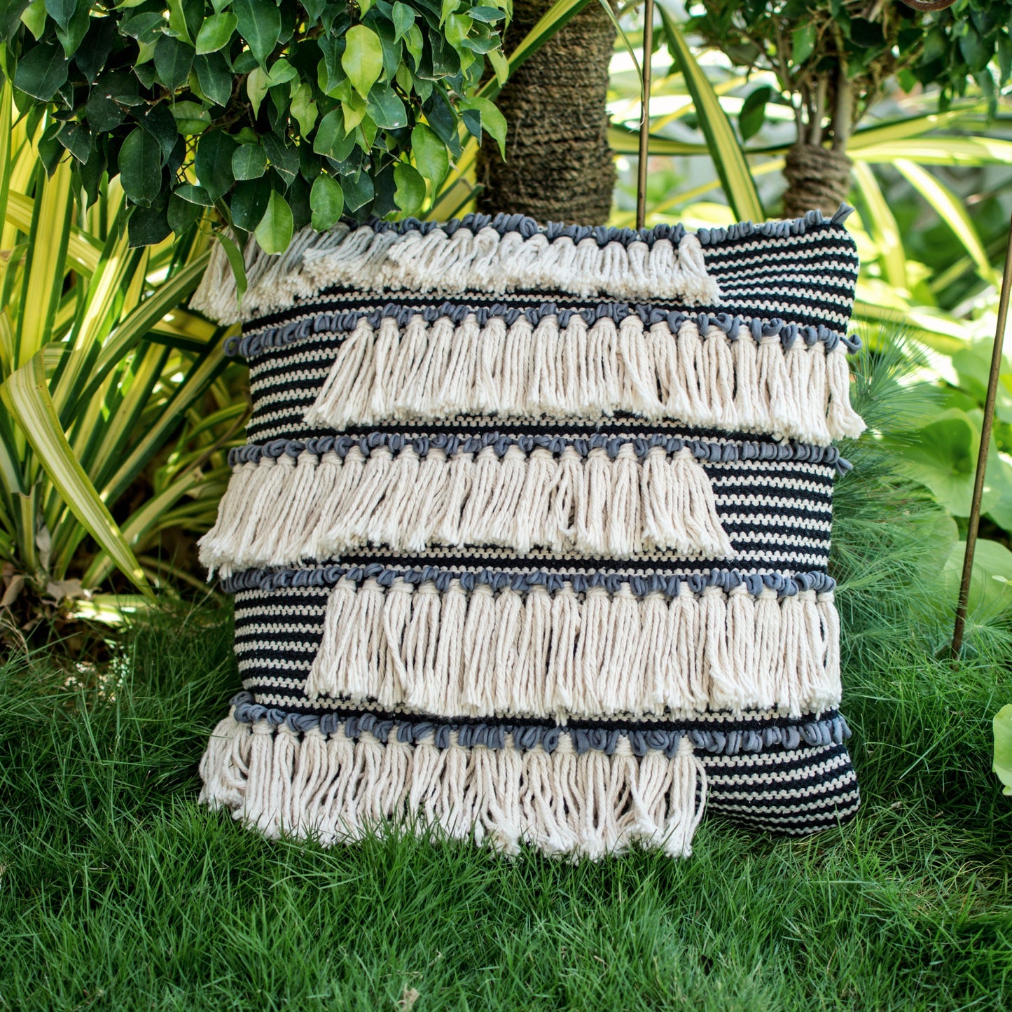 Avelina bohemian throw pillow with white tassels placed in an outdoor setting.