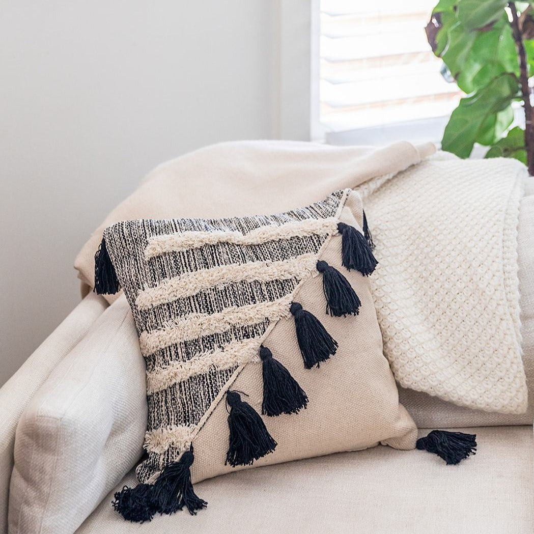 Bagru Bohemain throw pillow with black tassels complimenting a white couch